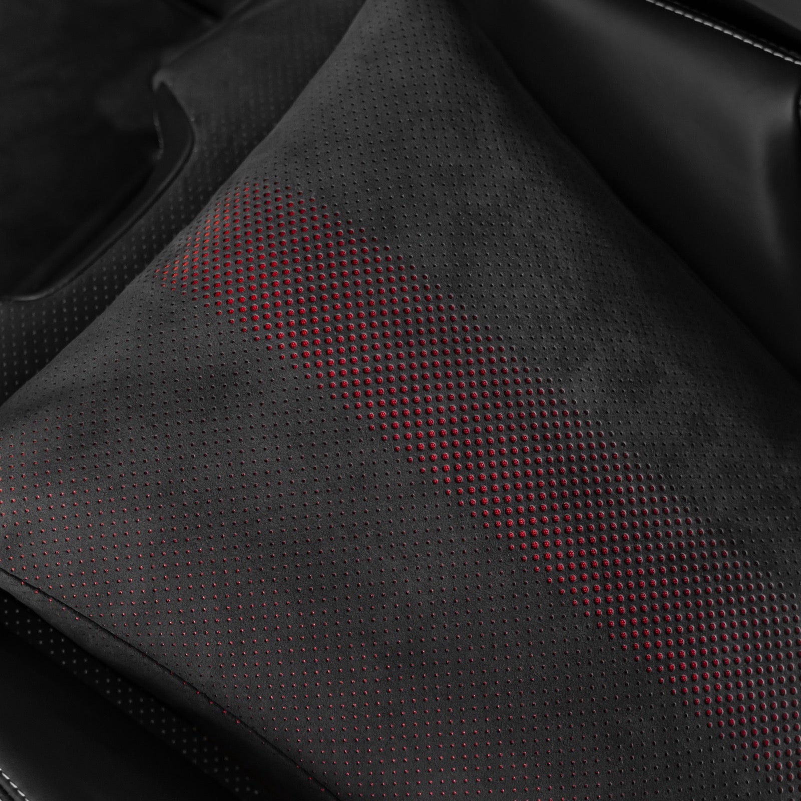 Close up of the black Alcantara fabric with red perforated dot pattern on a Porsche 992.2 space increase pillow