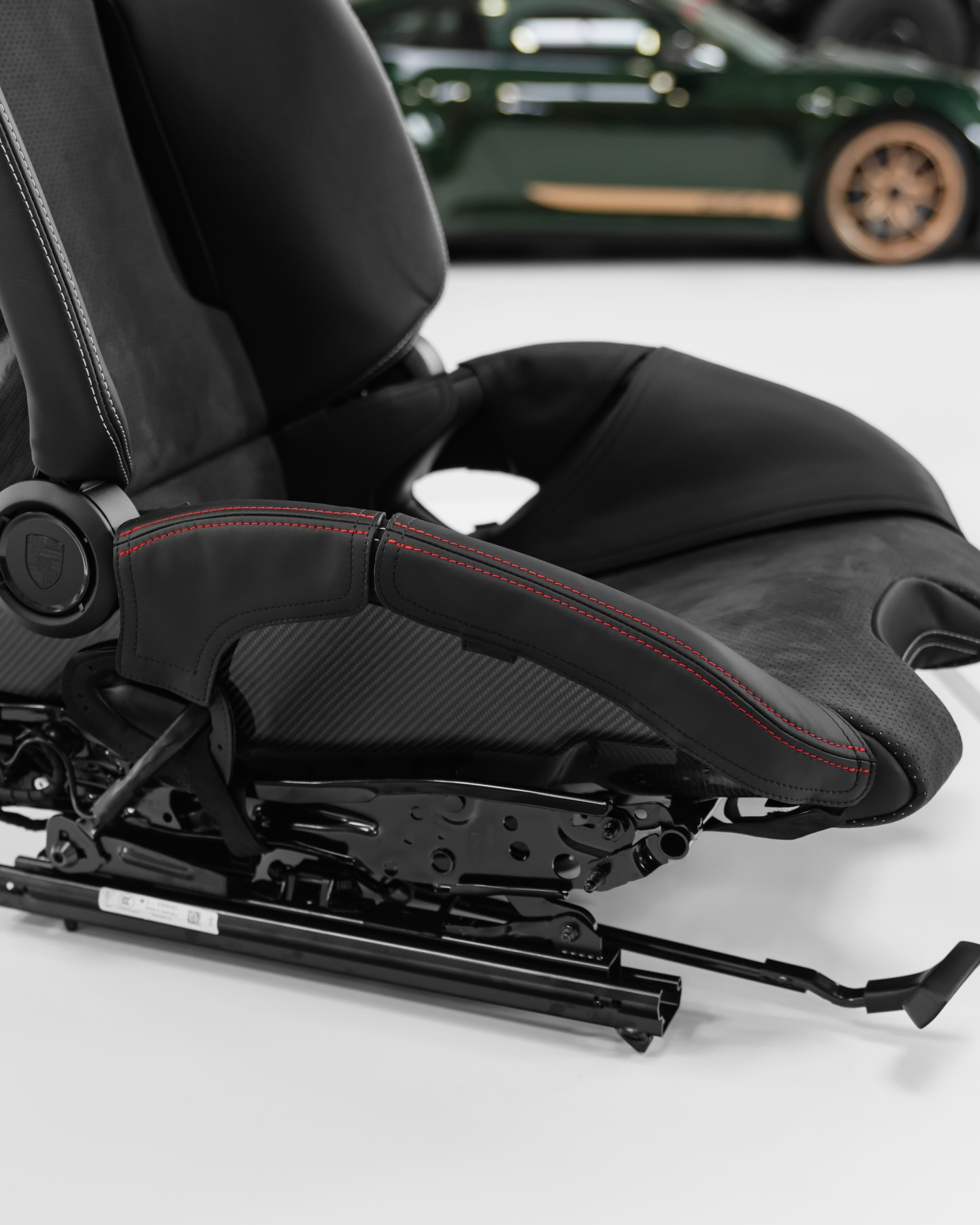 Porsche 992.2 folding bucket seat bolster protector on display, black Alcantara, red stitching