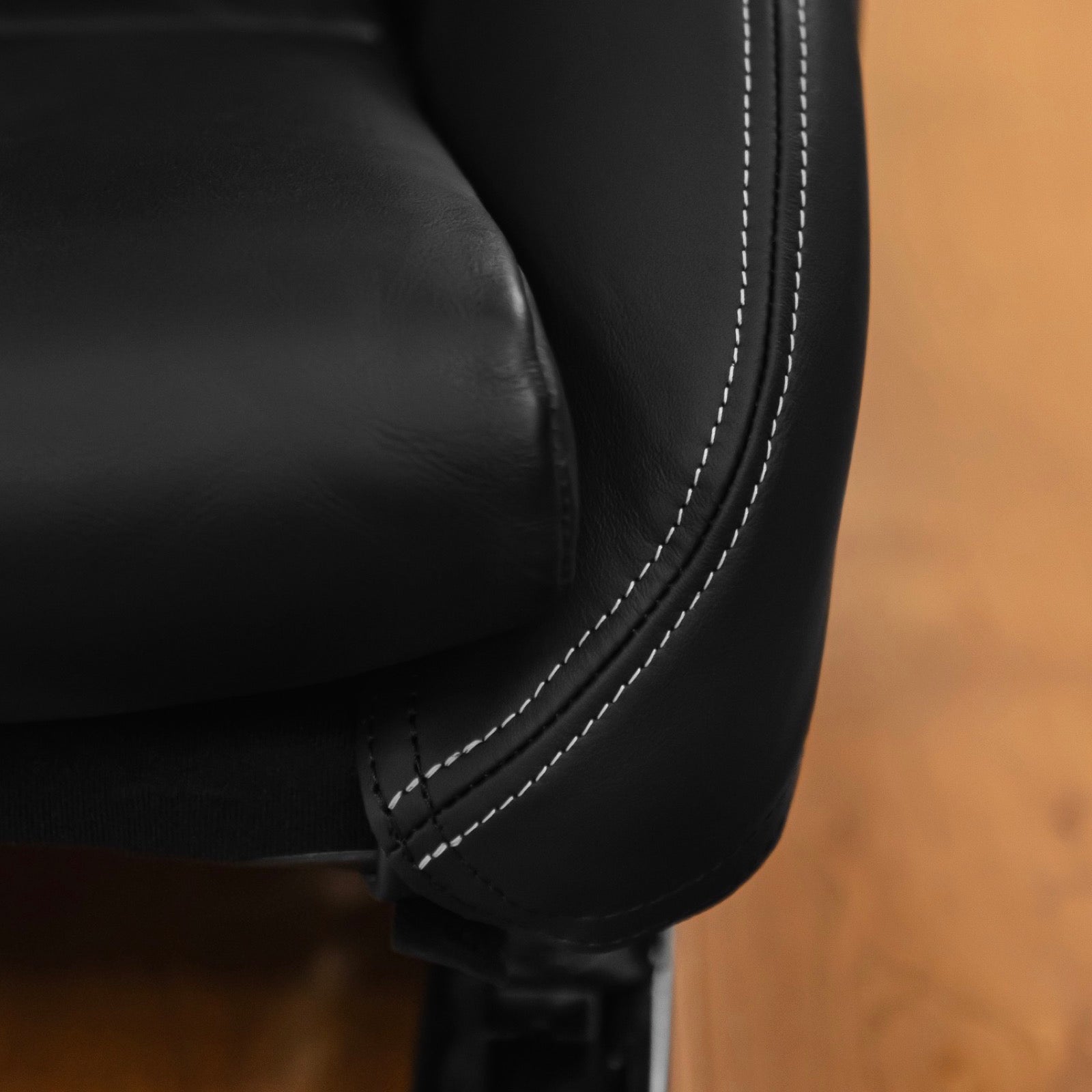 Close up of the double white contrast stitching on the edge of a black leather Porsche 997 seat bolster protector