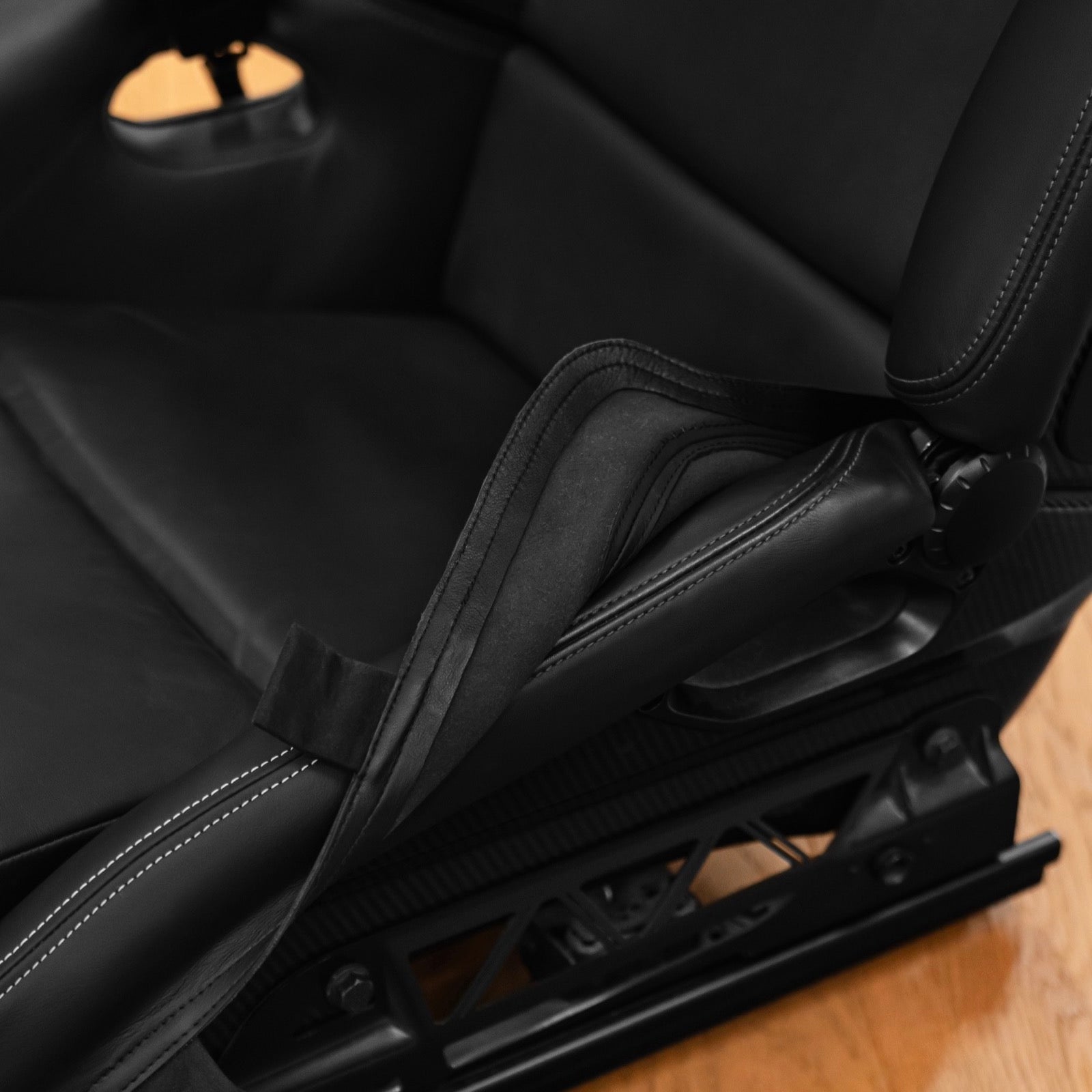 Porsche 997 seat bolster protector lifted from the seat showing the fastening straps and soft protective backing